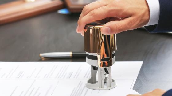 a hand holding a stamp, stamping a document