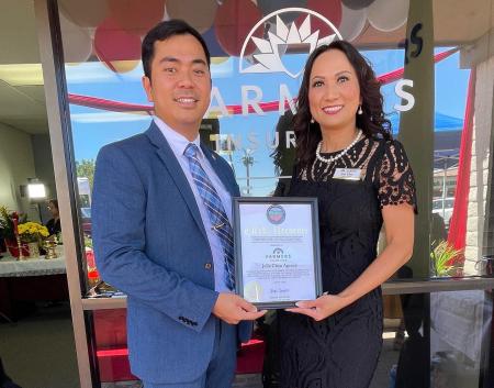 Outreach staff presenting a certificate of recognition to Julie Chau of Farmers Insurance.